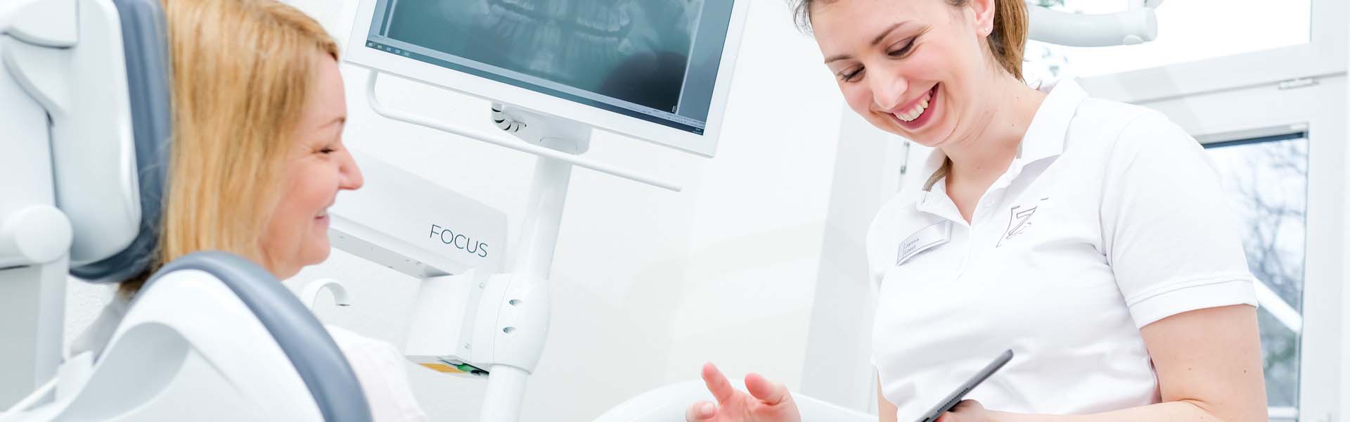 Zahnärztin Janina Kues veranschaulicht einer Patientin etwas via iPad